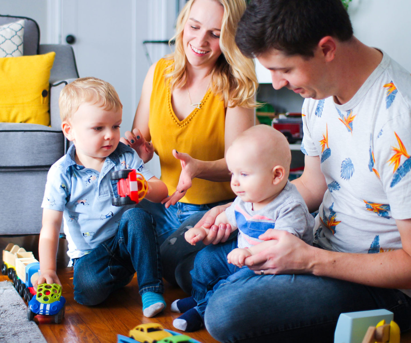 family with a toddler and baby playing on the floor with toys