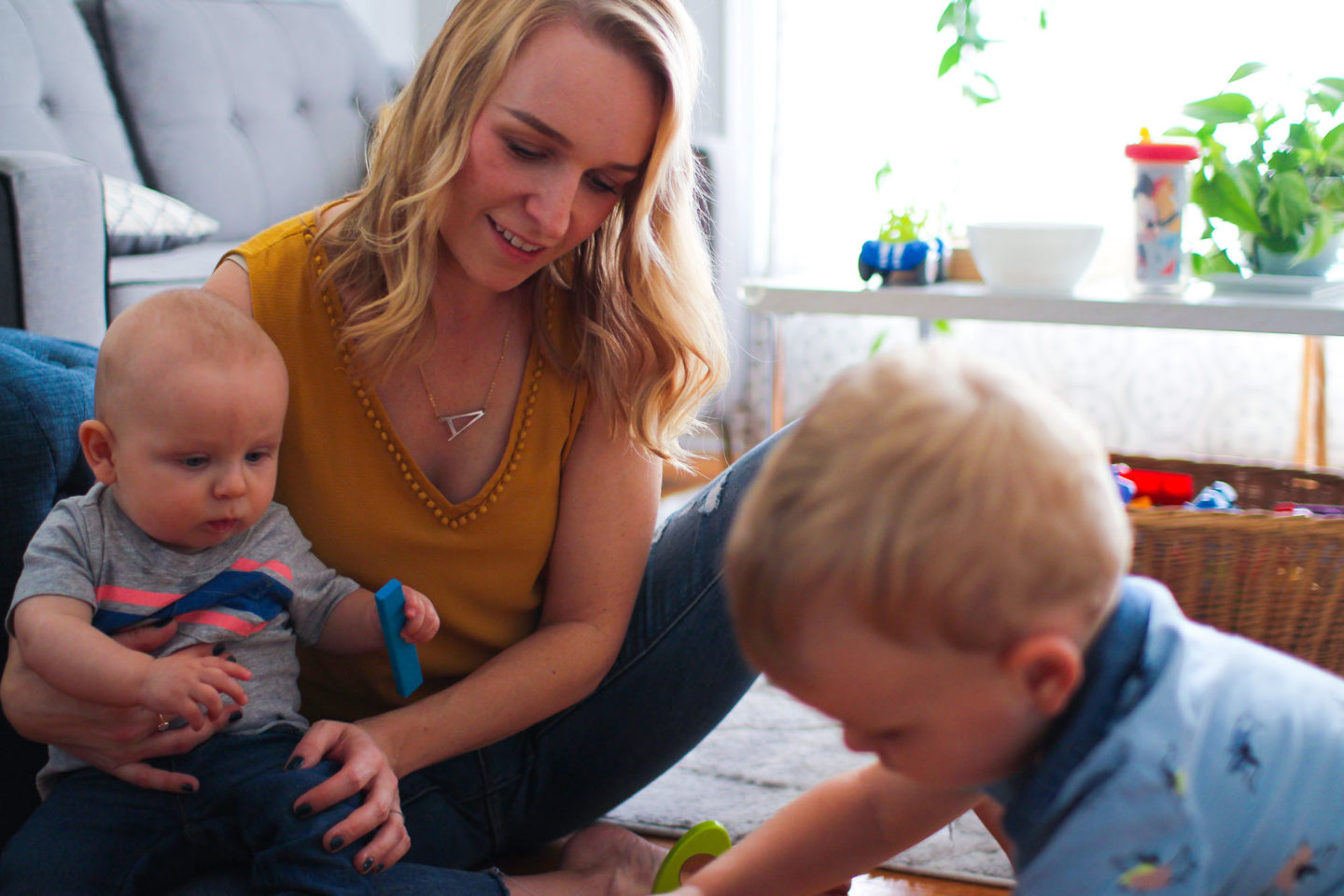 mom playing with toddler and baby on the floor