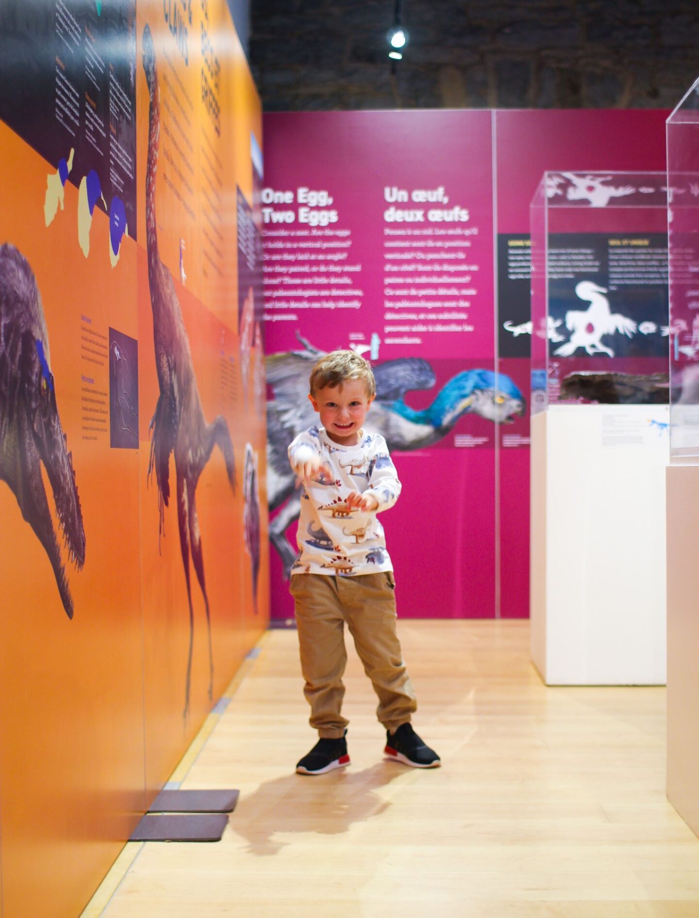 little boy pretending to be a dinosaur with teeth and claws at the dinosaurs among us exhibit in kingston